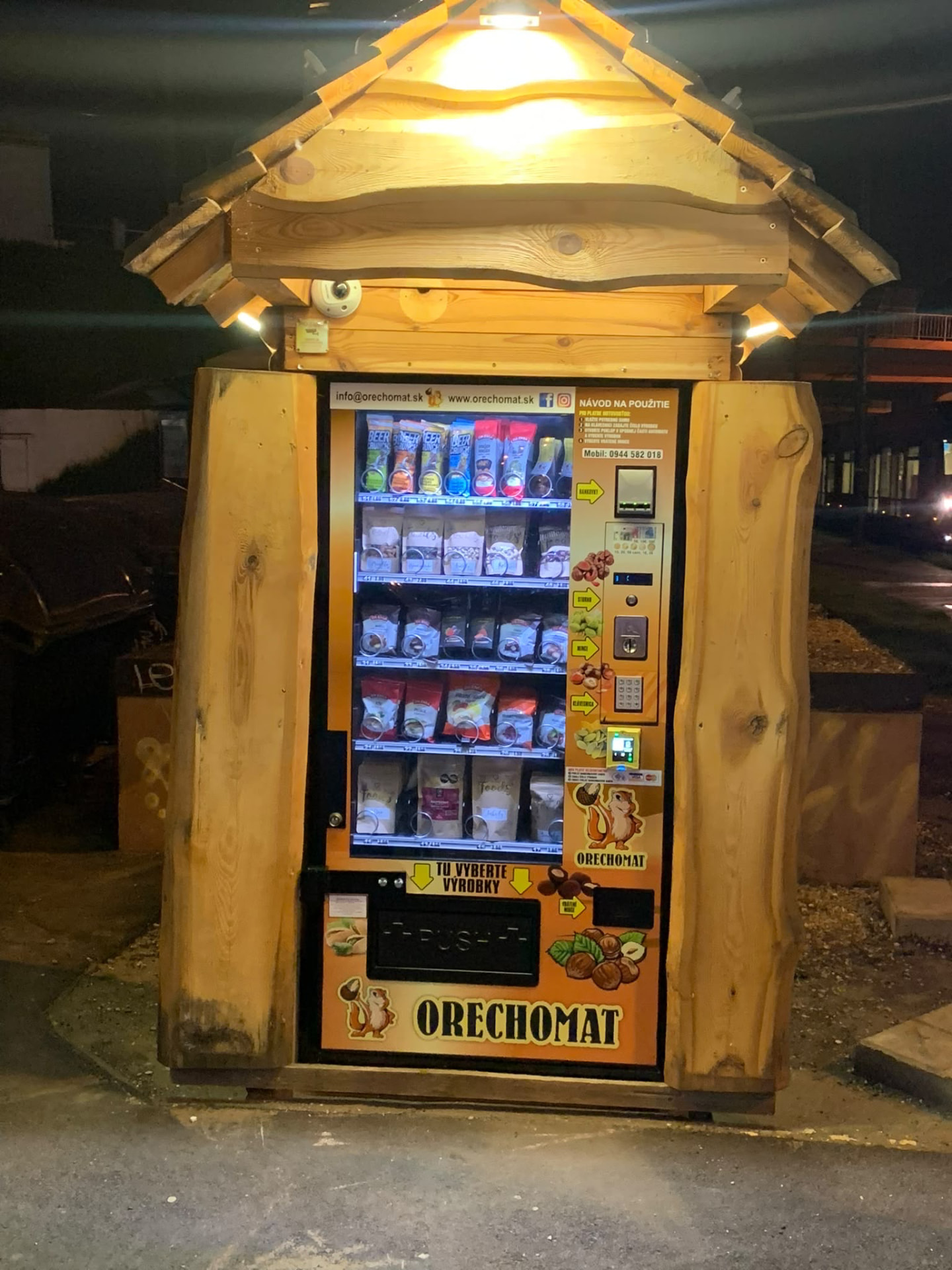 Osvietený Orechomat automat v drevenom stánku vonku večer